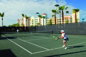 
a man holding a tennis racquet on a tennis court at Hammock Beach Golf Resort & Spa in Palm Coast
