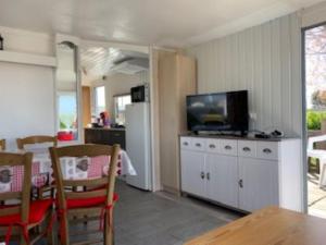 a kitchen and dining room with a table and a television at Mobilhome 4pers avec terrasse in Saint-Martin-aux-Buneaux