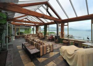 une véranda avec des canapés et des chaises ainsi qu'un grand plafond en verre dans l'établissement Wood Quay - A truly unique, seafront experience!, à Carlingford