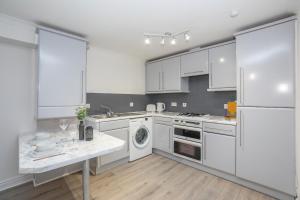 a kitchen with white cabinets and a washer and dryer at Panacotta House - Luxury 1 Bed Apartment in Aberdeen in Aberdeen