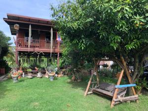 un patio con una casa con un árbol y un columpio en Metha Country View Homestay Singburi, en Ban Kho Sai