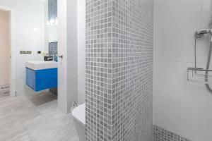 a bathroom with a white tiled wall and a sink at ApartUP Patacona Azzure in Valencia