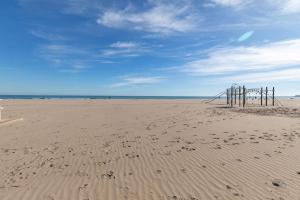 a beach with a wooden fence in the sand at ApartUP Patacona Azzure in Valencia