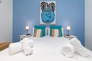 a bedroom with a large white bed with blue walls at ApartUP Patacona Azzure in Valencia