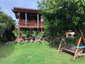 a house with a deck and a yard with plants at Metha Country View Homestay Singburi in Ban Kho Sai
