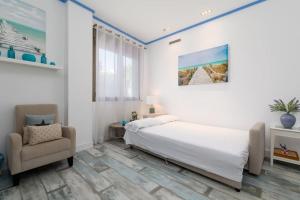 a white bedroom with a bed and a chair at ApartUP Patacona Azzure in Valencia