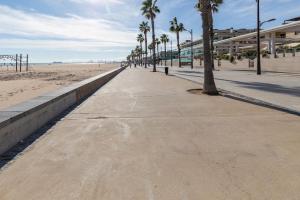 a sidewalk next to a beach with palm trees at ApartUP Patacona Azzure in Valencia