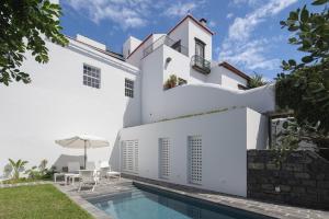 a white house with a swimming pool and a patio at Solar de Santo André in Ponta Delgada