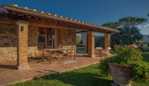 a brick house with a patio with a table and chairs at Villa Siloral Blu in Donoratico