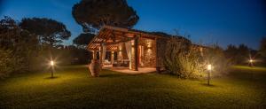 un pabellón de madera con luces en el césped por la noche en Villa Siloral Blu, en Donoratico