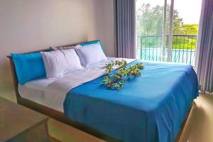 Una cama azul con flores y una ventana en Lakeville Residence en Nuwara Eliya