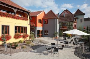 d'une terrasse avec des tables, des chaises et un parasol. dans l'établissement Les Portes de la Vallee, à Turckheim