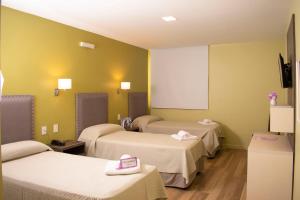 um quarto de hospital com três camas e um ecrã em Las Hortensias Hotel em Monteros