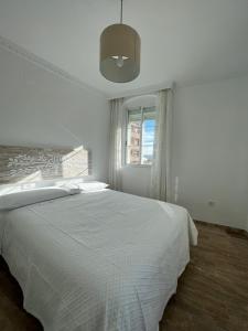 Un dormitorio blanco con una cama y una ventana. en BALCÓN DE CLAUDIO MARCELO, en Córdoba