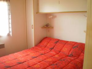 Cama en habitación con manta naranja en Gîte les Roziers, en Montmurat