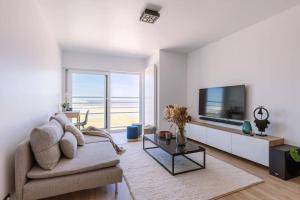 uma sala de estar com um sofá e uma televisão de ecrã plano em Cozy apartment with beautiful seaview em Knokke-Heist