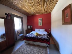 a bedroom with a bed with a red wall at Wolverfontein Karoo Cottages in Ladismith