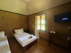 a bedroom with two beds and a television and a window at Babaland in New Agutaya