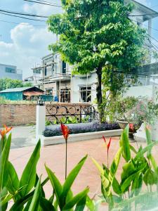 einen Garten mit einem Baum und Pflanzen vor einem Gebäude in der Unterkunft Mộc Hương Hotel in Phú Thọ