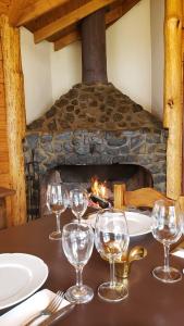 a group of wine glasses on a table with a fireplace at Hostería Boutique Fuegos del Sur in Ushuaia