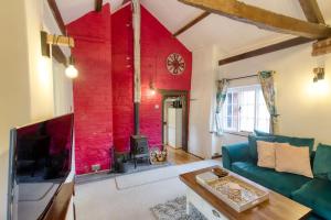 sala de estar con sofá y pared roja en White Cross Cottage, en Woodbury