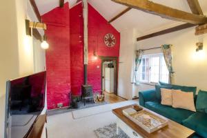 a living room with a couch and a red wall at White Cross Cottage in Woodbury