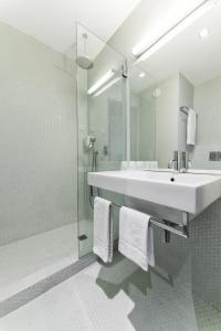 a white bathroom with a sink and a shower at Moov Hotel Porto Centro in Porto