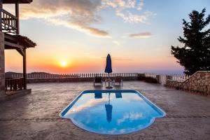 - une piscine sur une terrasse avec un coucher de soleil en arrière-plan dans l'établissement Vissala Village, à Chortáta
