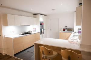 cocina con armarios blancos y encimera en Exquisite cozy house, close to Train Station and amenities en Harold Wood
