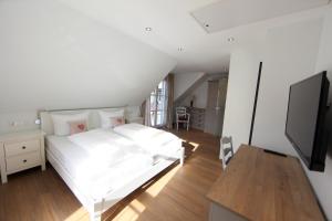 Schlafzimmer mit einem weißen Bett und einem Flachbild-TV in der Unterkunft Ferienhaus Christina in Bad Windsheim