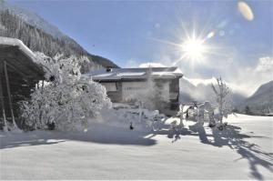 a building covered in snow with the sun behind it at Hotel LÄRCHENHOF in Kleinarl