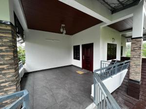 a porch of a house with a red door at Cherry Blossom Munnar- 2 Bedroom Homestay in Munnar