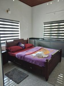 a bedroom with a bed with purple sheets and windows at Munnar Home stay in Munnar