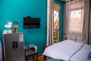 a bedroom with a refrigerator and a blue wall at Unia fancy flats studio Apartment one in Kampala