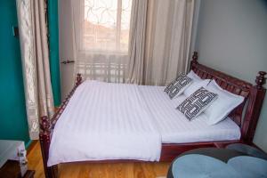 a bedroom with a bed with pillows and a window at Unia fancy flats studio Apartment one in Kampala
