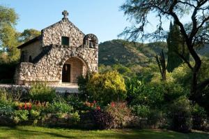 un pequeño edificio de piedra en un jardín con flores en CASA15Golf Potrerillo de Larreta en Alta Gracia