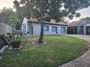 une maison avec un arbre dans la cour dans l'établissement Le Grix Guesthouse, à Nelspruit