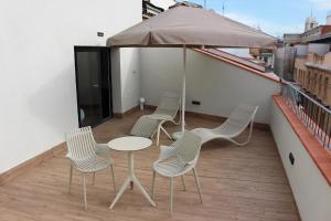 4 sillas y una mesa en un balcón con sombrilla en Apartamentos Centro Jardines, en Madrid