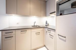 uma cozinha com armários brancos e um lavatório em LAAX Homes - Sisum La Spunda em Falera