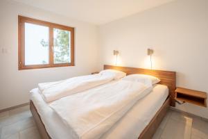 Duas camas grandes num quarto com uma janela em LAAX Homes - Sisum La Spunda em Falera