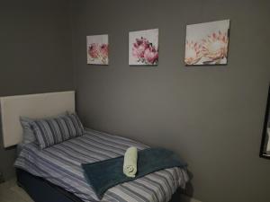1 dormitorio con 1 cama y 4 cuadros en la pared en Le Grix Guesthouse, en Nelspruit