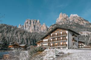 a hotel in the mountains with mountains in the background at Hotel Garnì Rosengarten in Pera