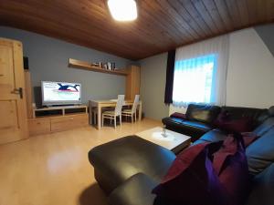 a living room with a couch and a table and a tv at Haus Rosina in Mühlbach am Hochkönig