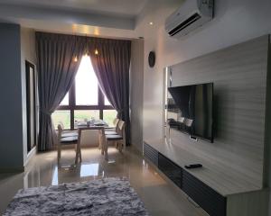 a living room with a television and a table with chairs at Bali Residence Impian Raudah in Melaka