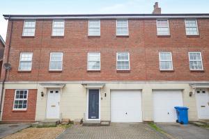 a brick building with two white garage doors at Luxurious and Modern 3 Bed townhouse with Parking in Norwich