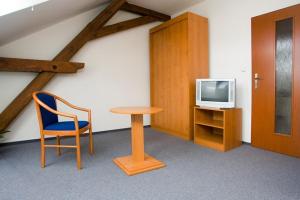 a room with a table and a chair and a tv at Pension Smetanuv statek in Hradec Králové