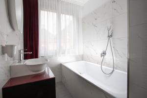La salle de bains blanche est pourvue d'une baignoire et d'un lavabo. dans l'établissement ARTIST Boutique Hotel, à Vienne