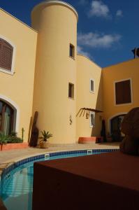 a house with a swimming pool in front of a building at El Mosaico Del Sol in Lampedusa