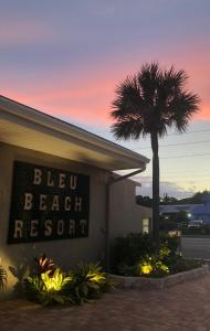 a sign for a beach resort with a palm tree at Bleu Beach Resort in Indialantic