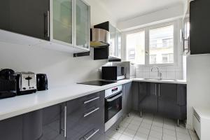 - une cuisine avec des plans de travail blancs et un évier dans l'établissement CMG Tour Eiffel/ New York, à Paris